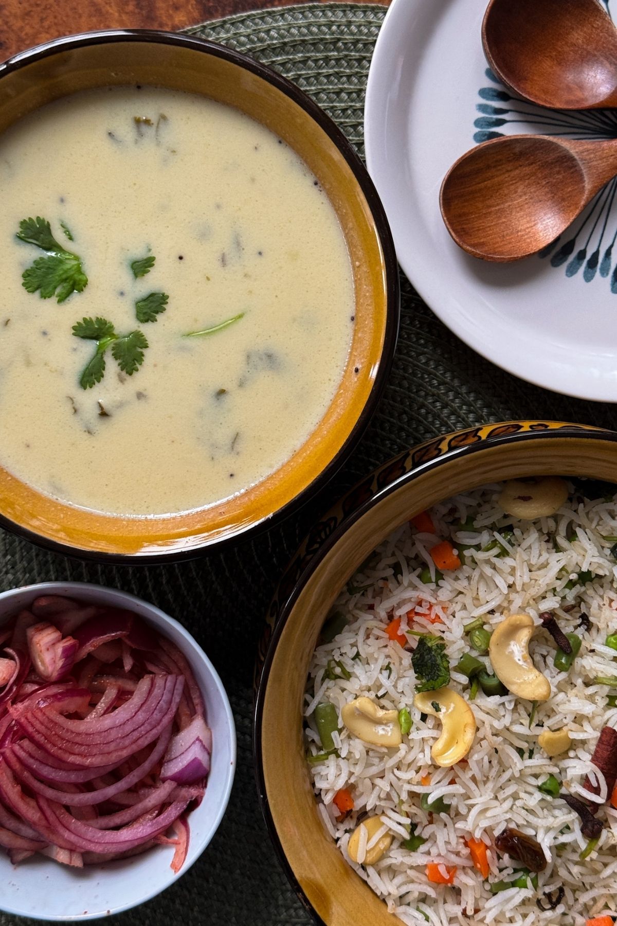 Gujarati Kadhi in a bowl with Pulav and Pickled Onions on the side