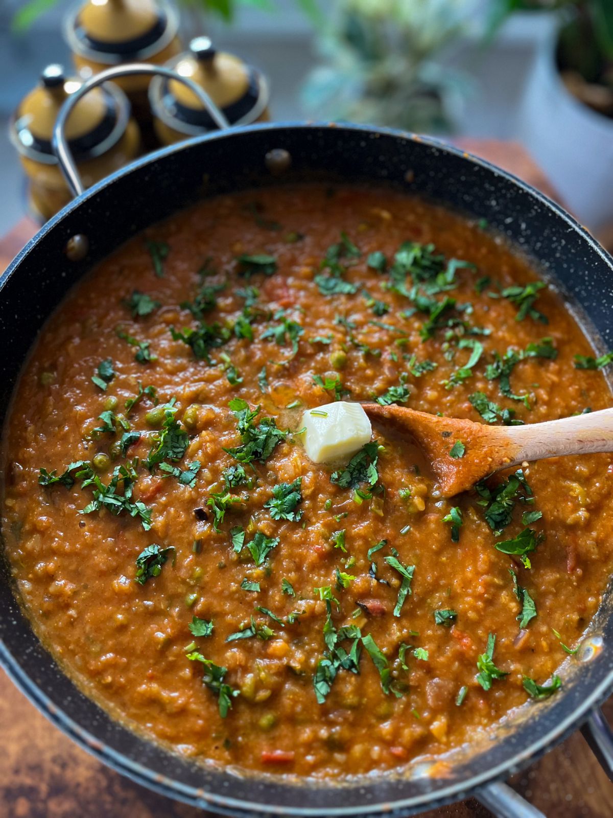 homemade mumbai street style pav bhaji in a pot with a cube of butter melting on the top and garnished cilantro