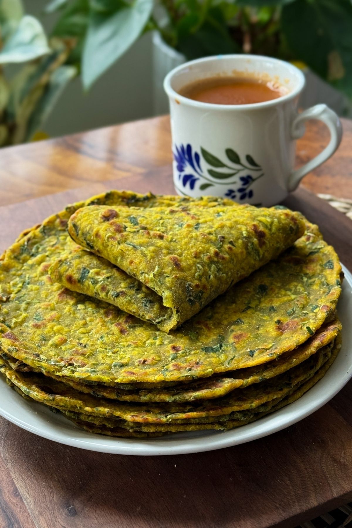 theplas stacked in a plate with a cup of masala chai