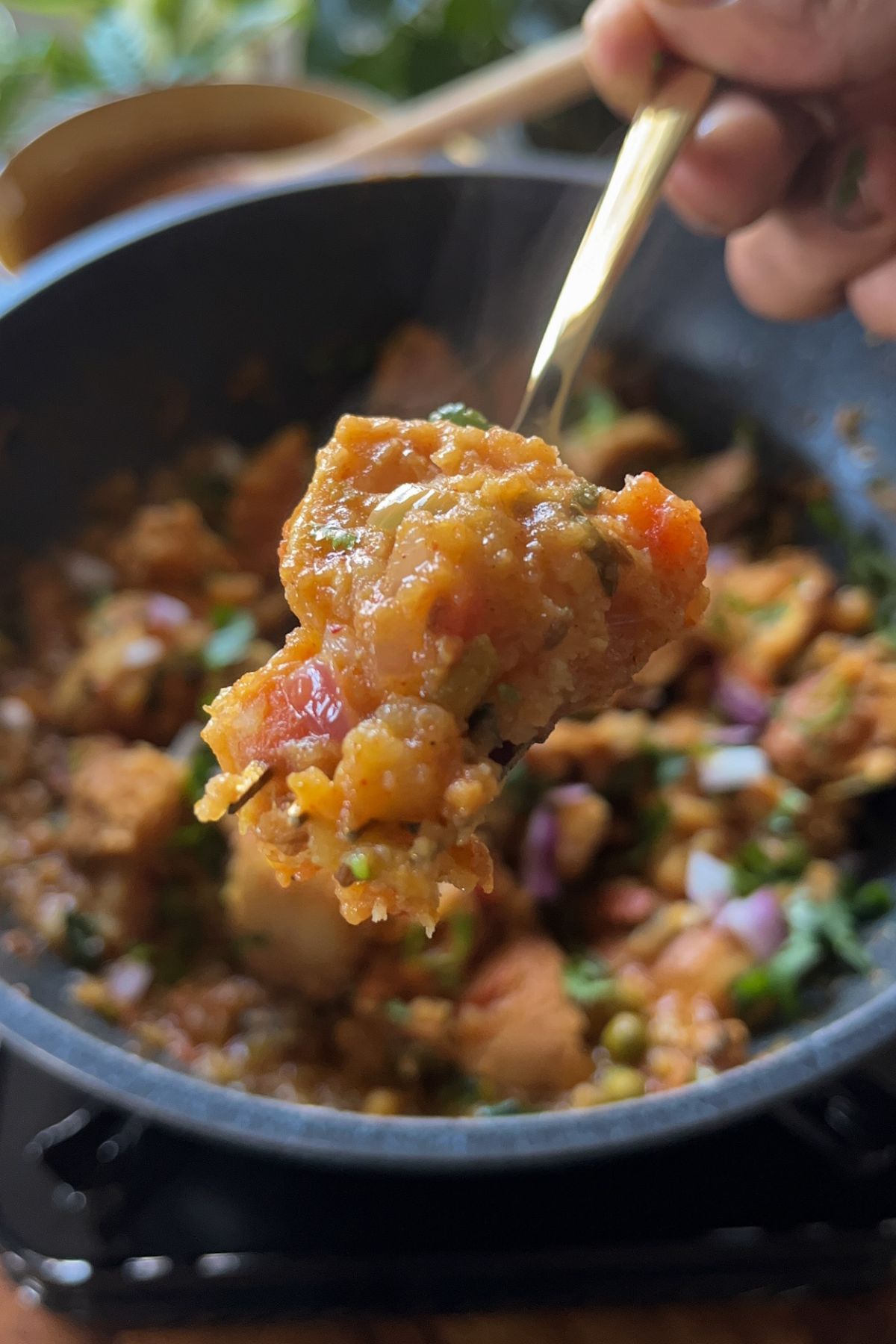 masala pav held with a fork out from a wok