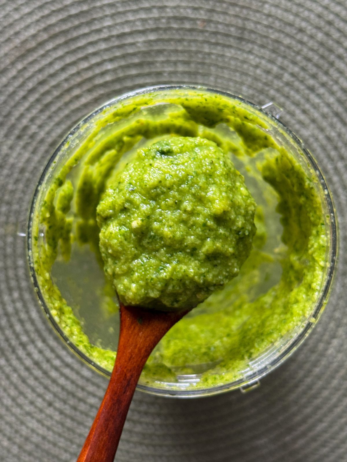 Green chutney being scooped with a wooden spoon from blender jar