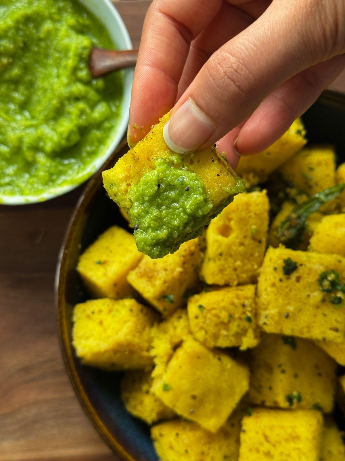 Vatidal khaman dipped in chutney with a big bowl